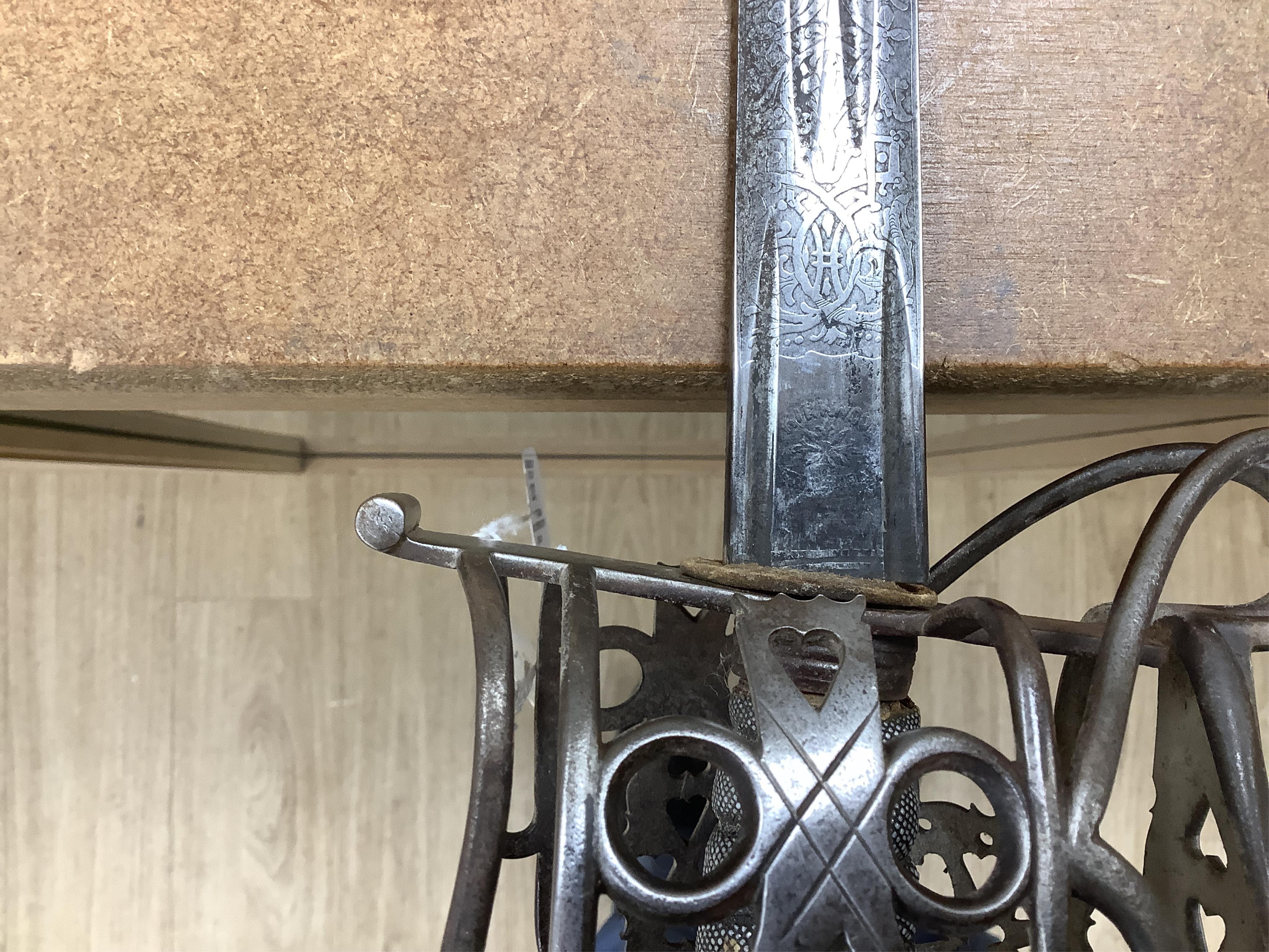 A late Victorian officer’s sword of the Black Watch, claymore blade etched with regimental title and VR cipher, regulation basket hilt, fish skin covered grip, in its leather covered field service scabbard, blade 82cm. C